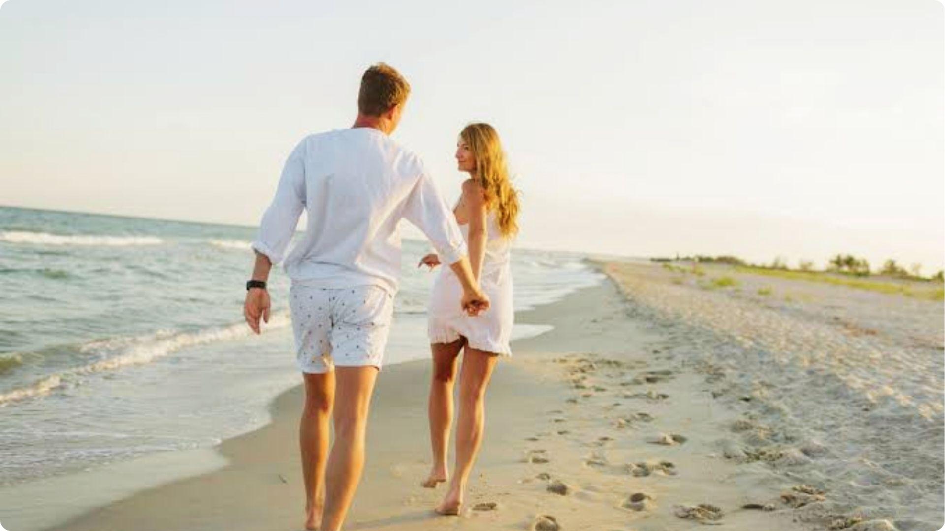 Romantic couple holding hands walking barefoot along sandy Myrtle Beach shoreline at sunset