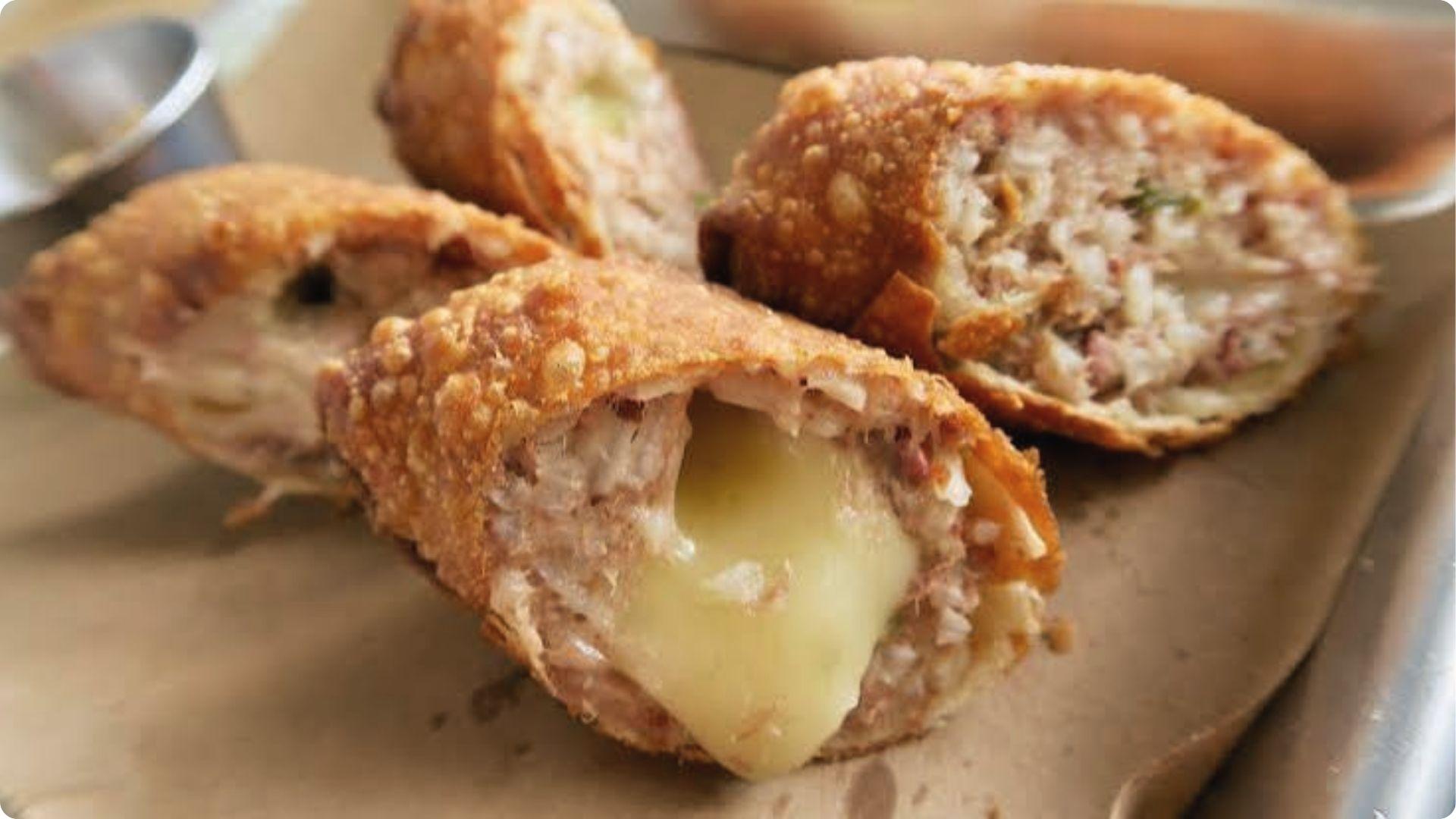 Crispy fried New Orleans boudin balls oozing melted cheese, popular Cajun street food appetizer.