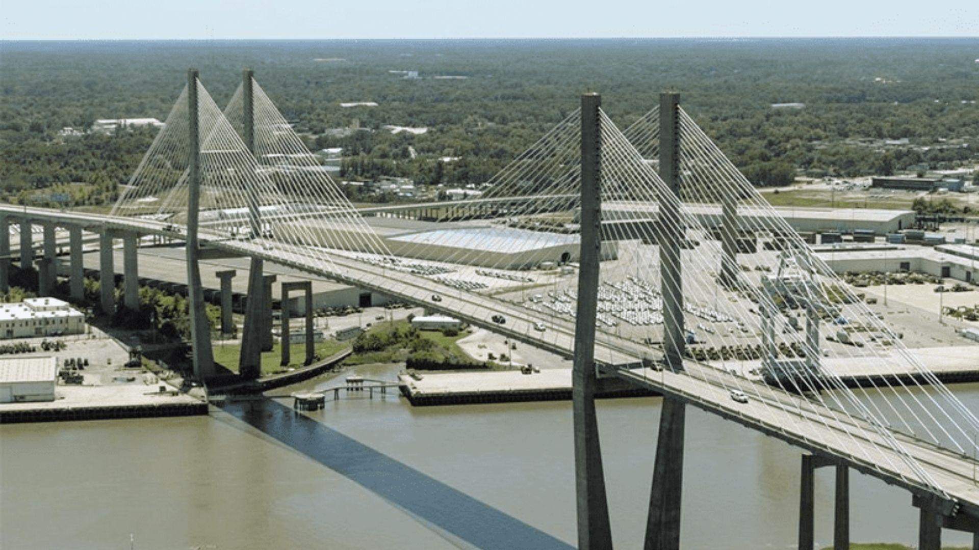 Aerial view of Talmadge Memorial cable-stayed bridge spanning river with traffic and industrial port below