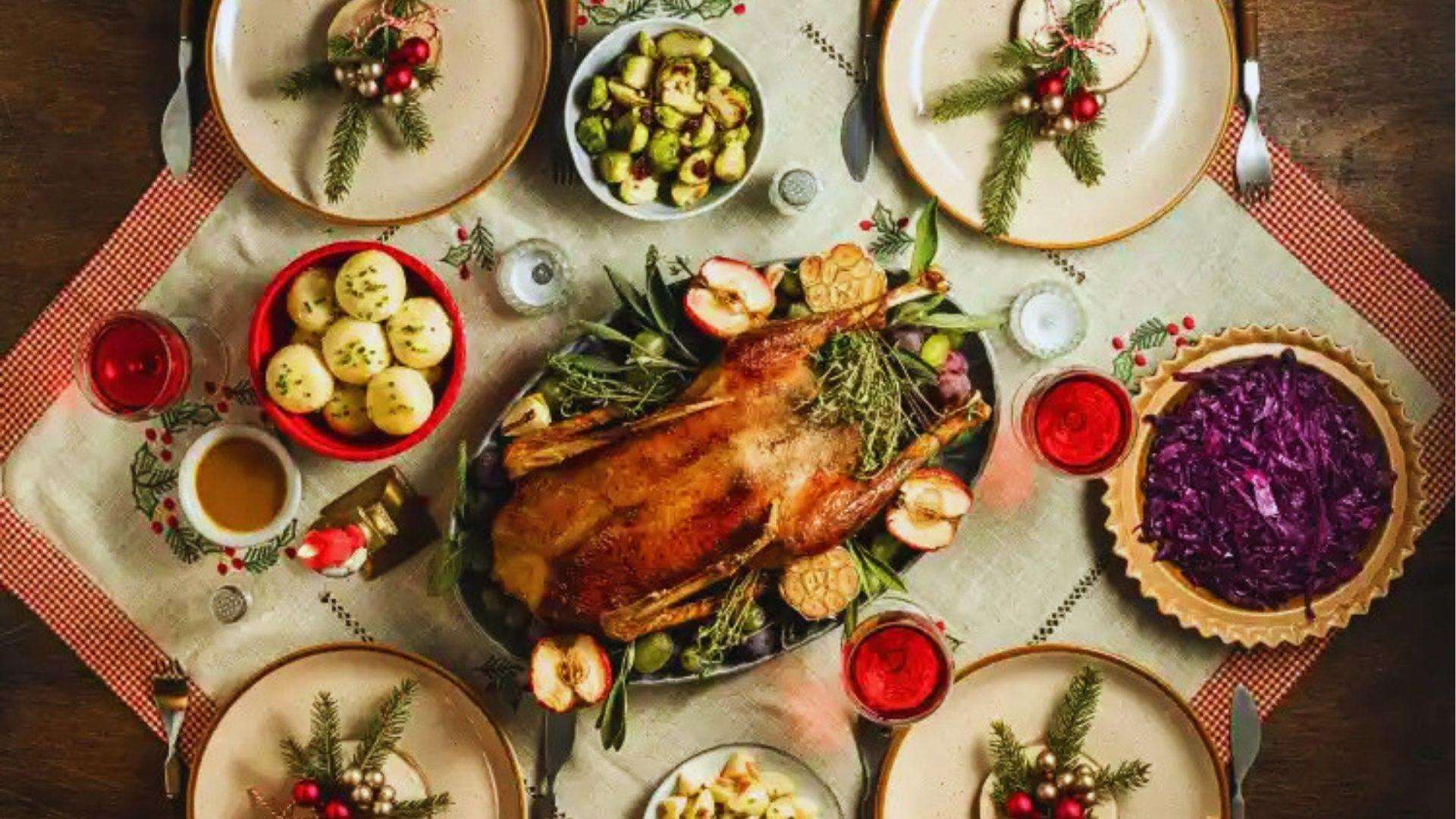 Festive Christmas dinner table set with roasted duck side dishes and holiday decorations from above.
