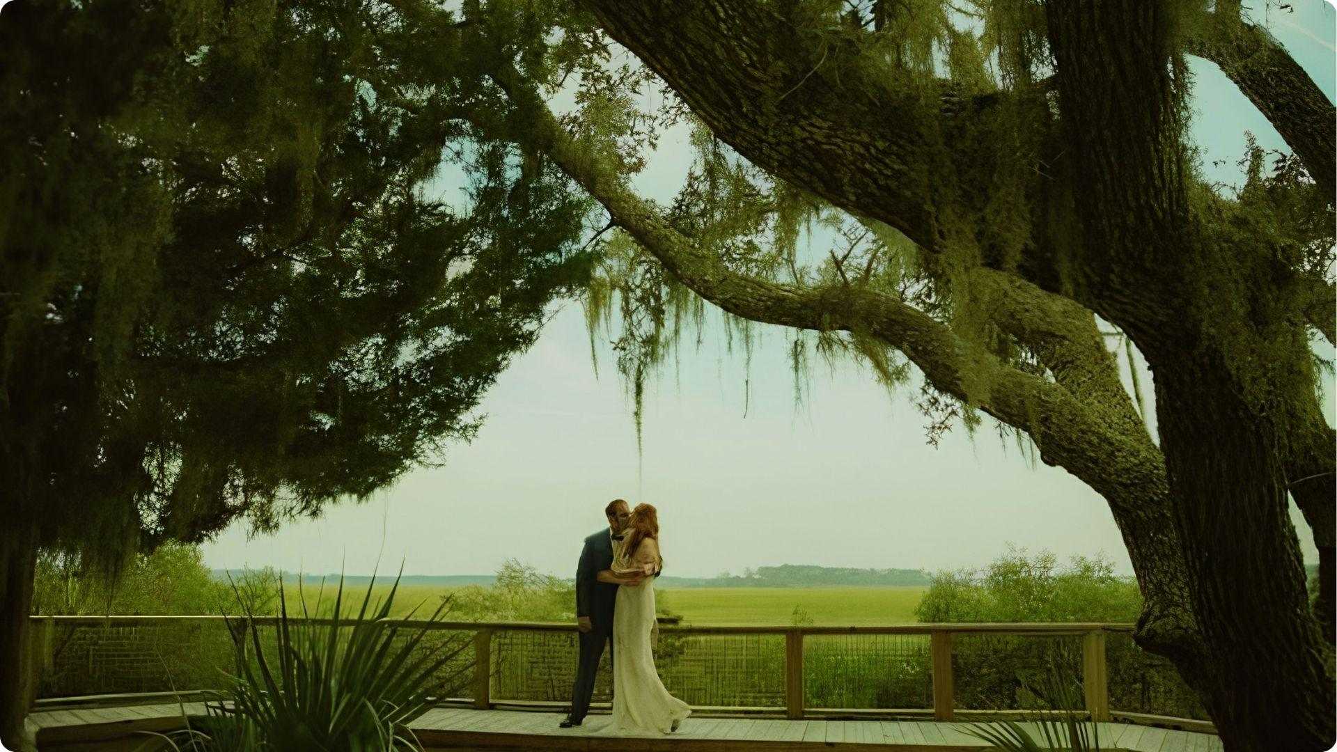 Couple embracing under moss-draped live oak overlooking marsh at Pin Point Heritage Museum