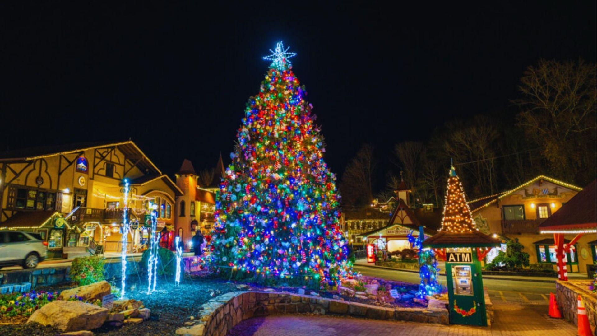 Brightly lit Christmas tree at night in Helen Georgia square with colorful lights and decorations.