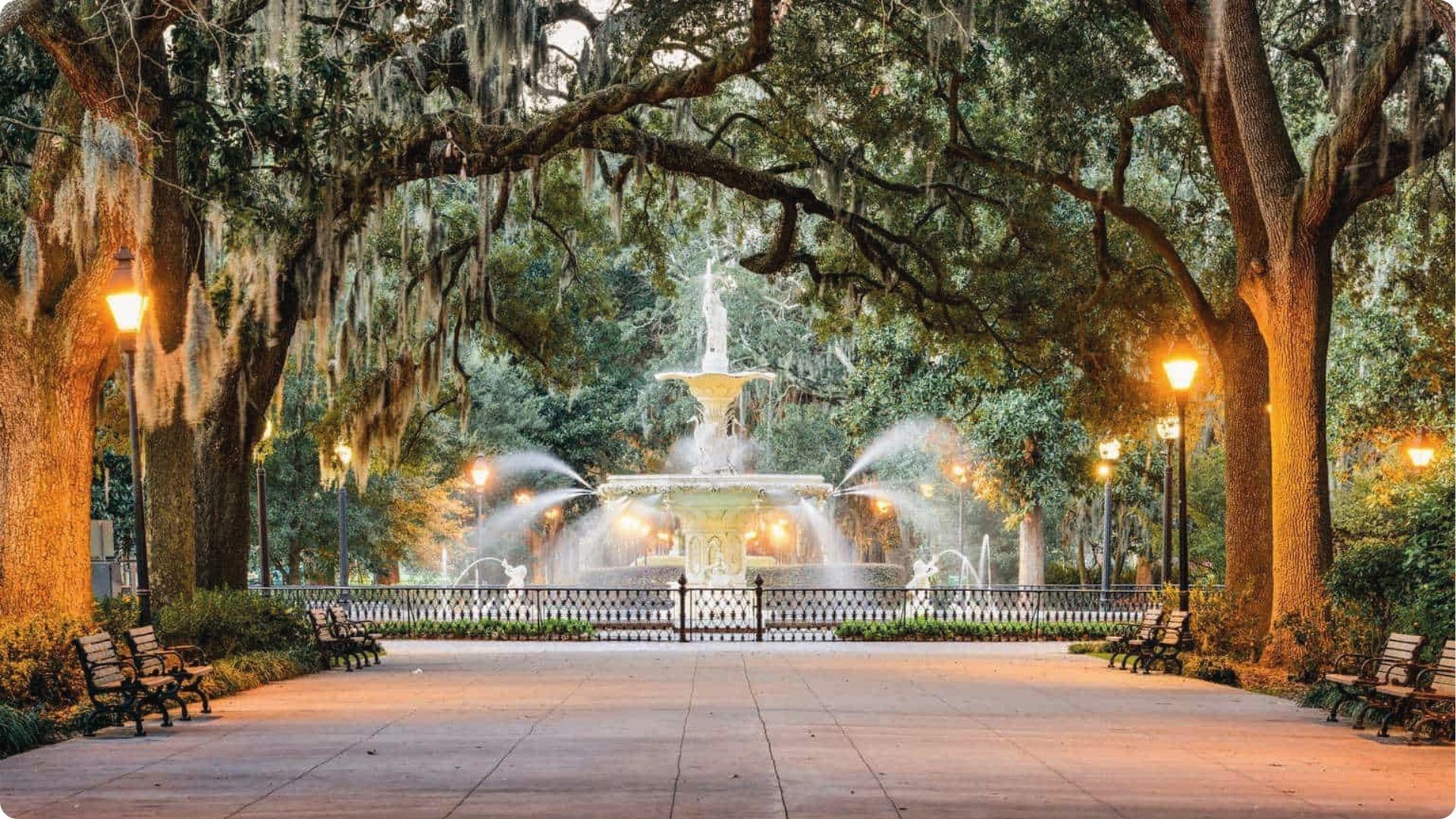 Forsyth Park fountain lit at dusk under mossy oaks, romantic finale point on Savannah walking tour map