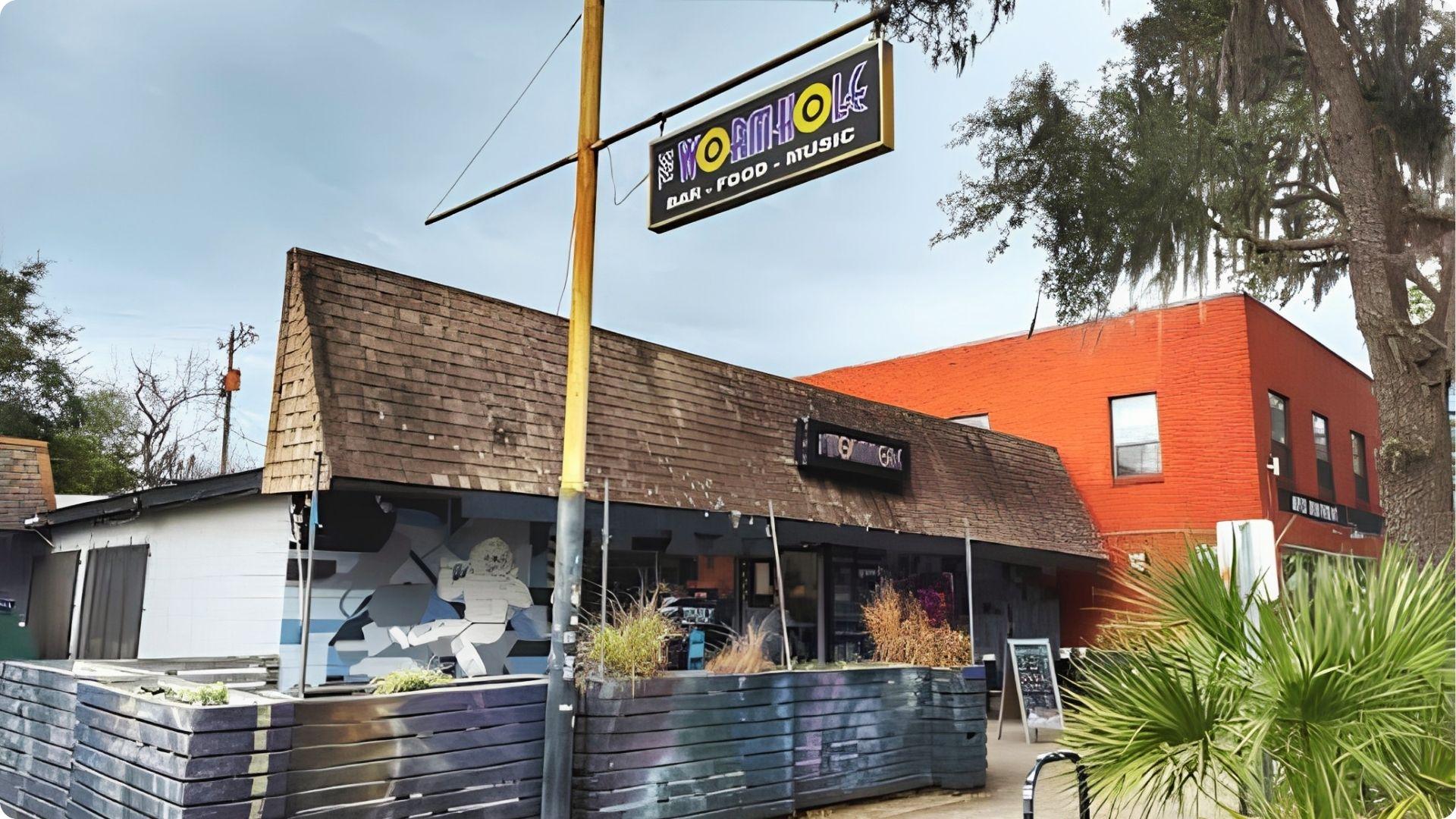 Wormhole Bar Food Music sign over quirky Savannah dive bar with patio seating for happy hour