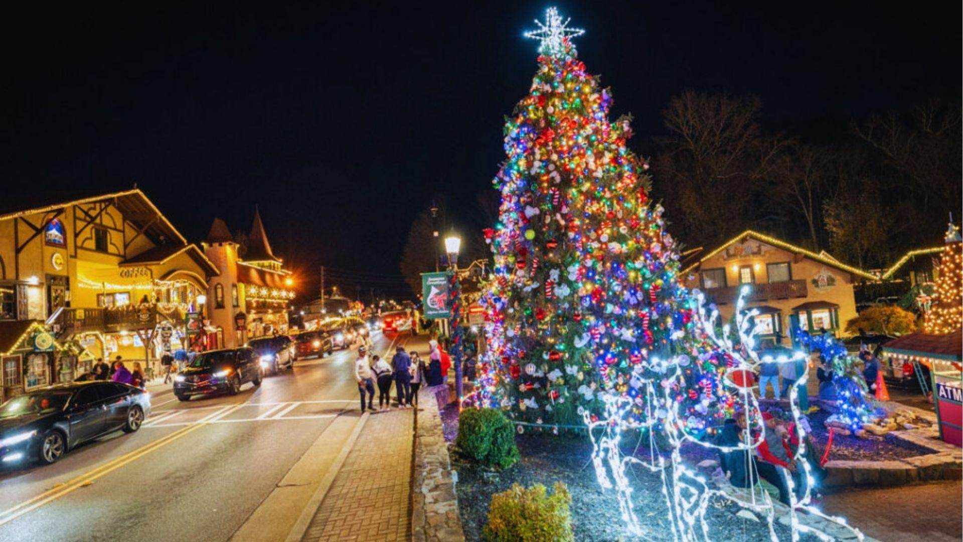 Illuminated Christmas tree with colorful ornaments and lighted reindeer on busy Helen street at night.