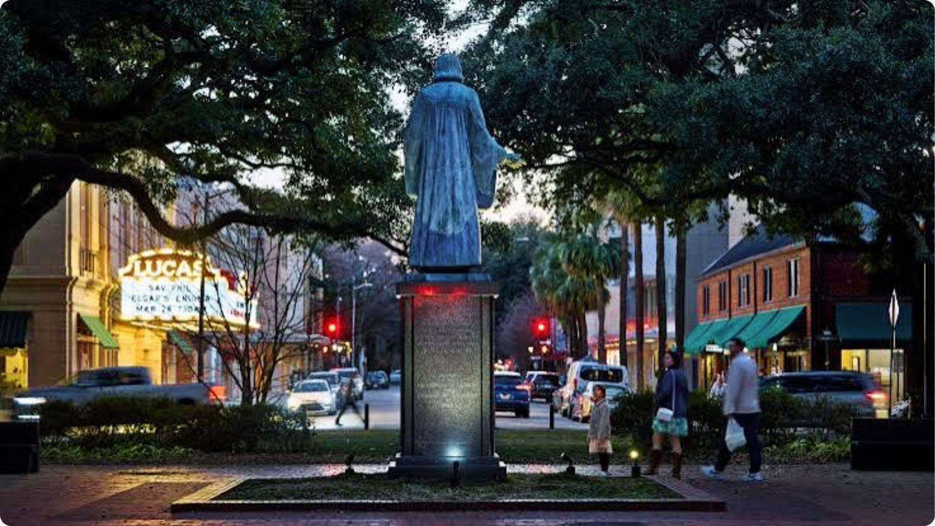 Savannah square with Wesley statue and Lucas Theatre lights glowing during happy hour stroll