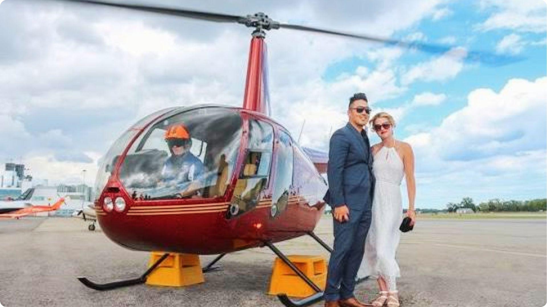 Red helicopter, and couple smiling toward the camera romantic air tour for couples.
