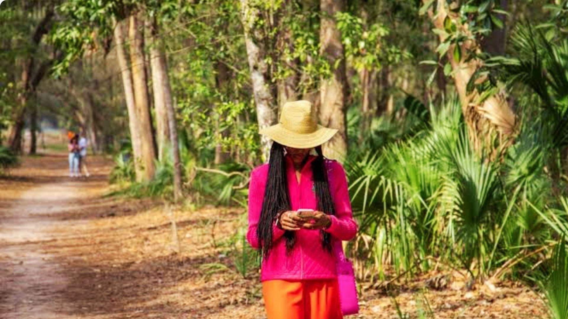 Woman walking on shaded nature trail with palmettos in Savannah Georgia in October