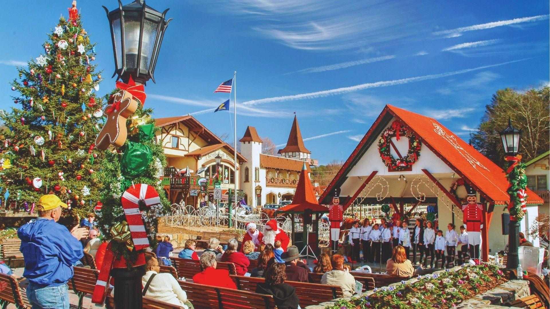 Outdoor Christmas stage with children choir performing beside decorated trees and holiday decorations for the crowd.