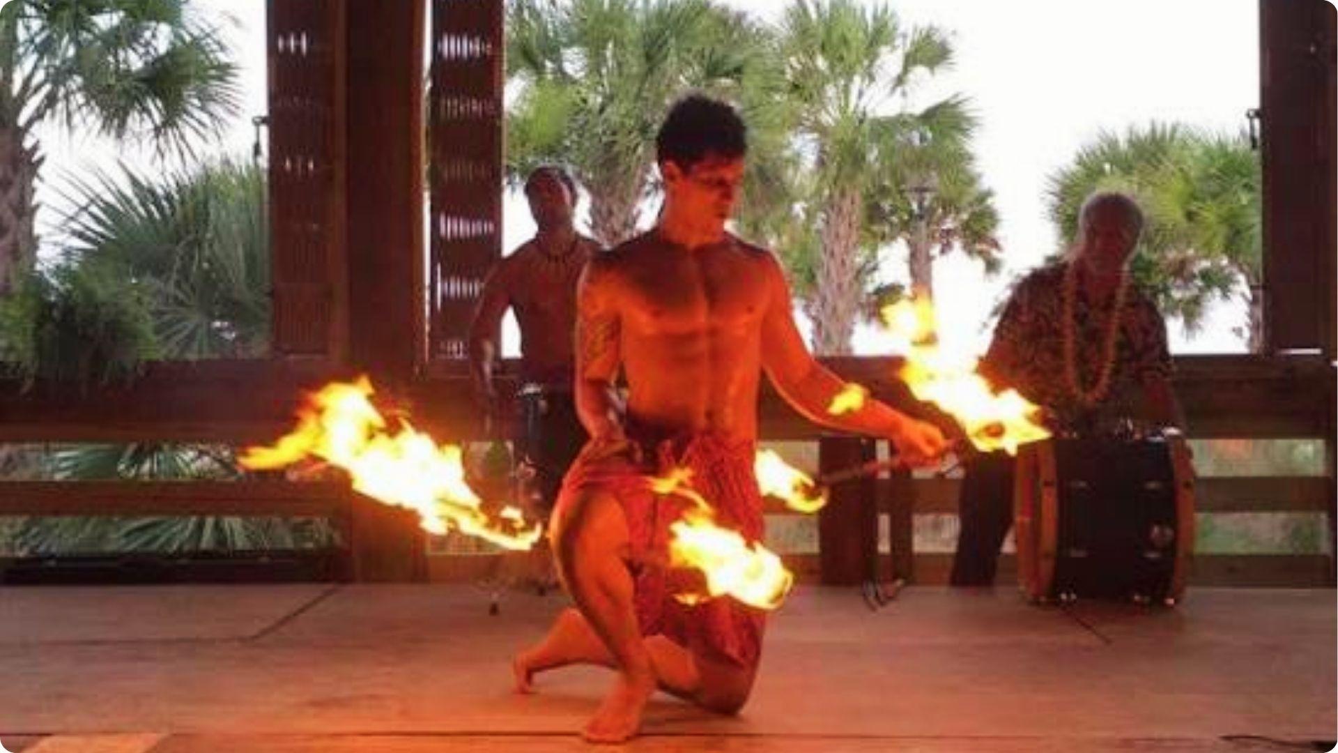 Fire dancer performing with flaming torches at beachside luau show for couples in Myrtle Beach