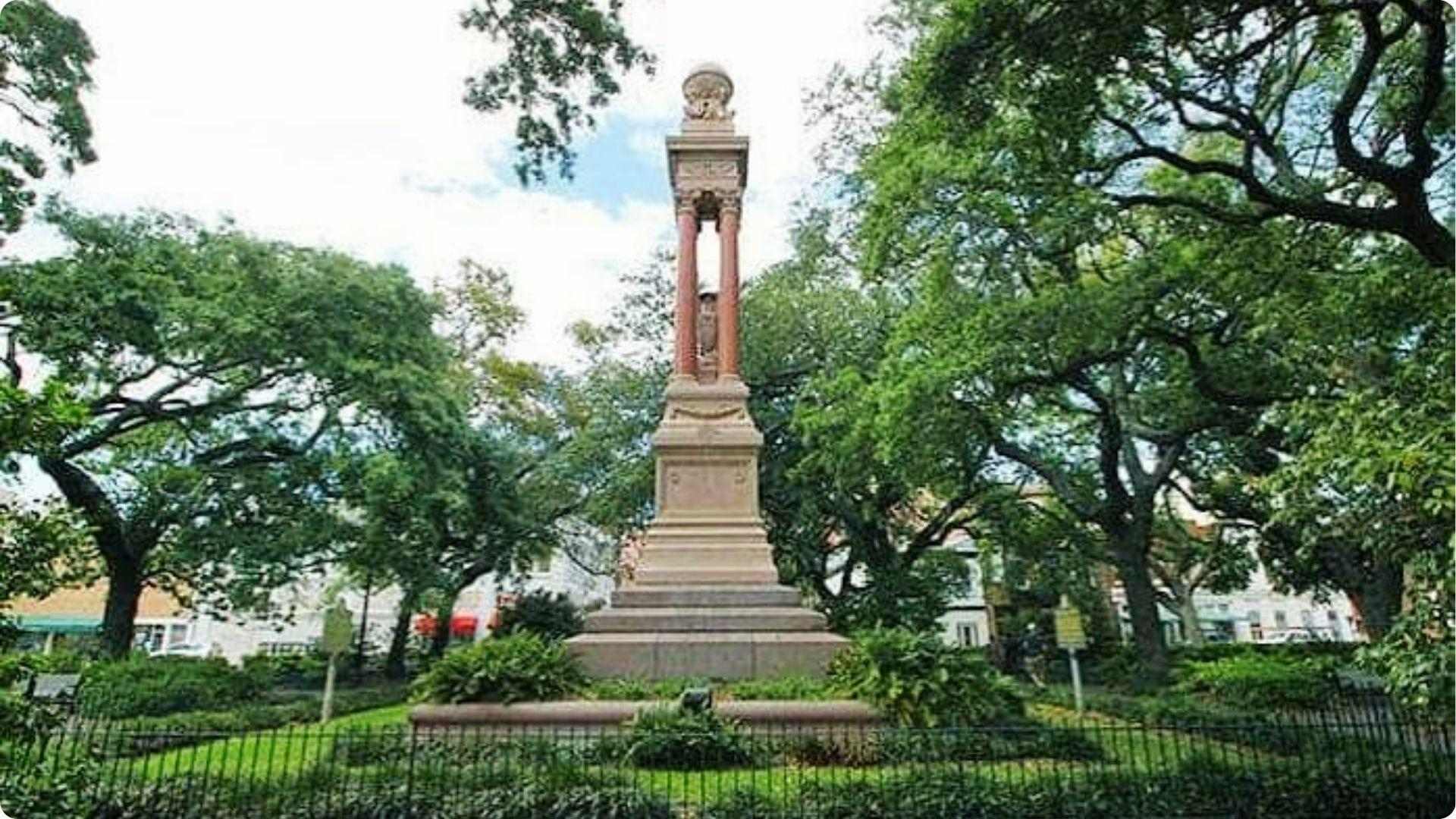 A historic monument with tall columns stands in shady Savannah square surrounded by live oaks tour landmarks.