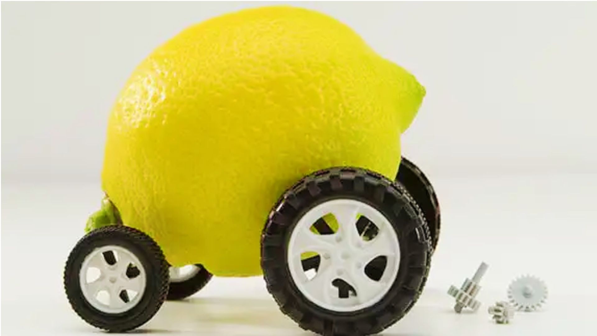 Lemon with toy wheels and scattered gears symbolizing defective lemon car under Georgia law