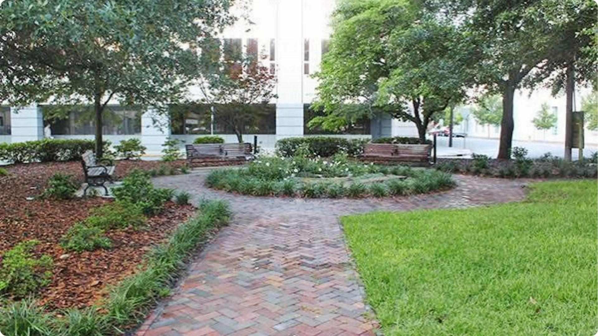 Brick herringbone path winds through Savannah pocket park with benches and lush greenery tour stop.