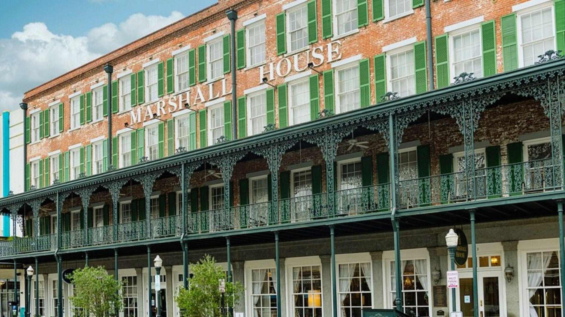Marshall House hotel red brick facade with green shutters and ornate iron balcony