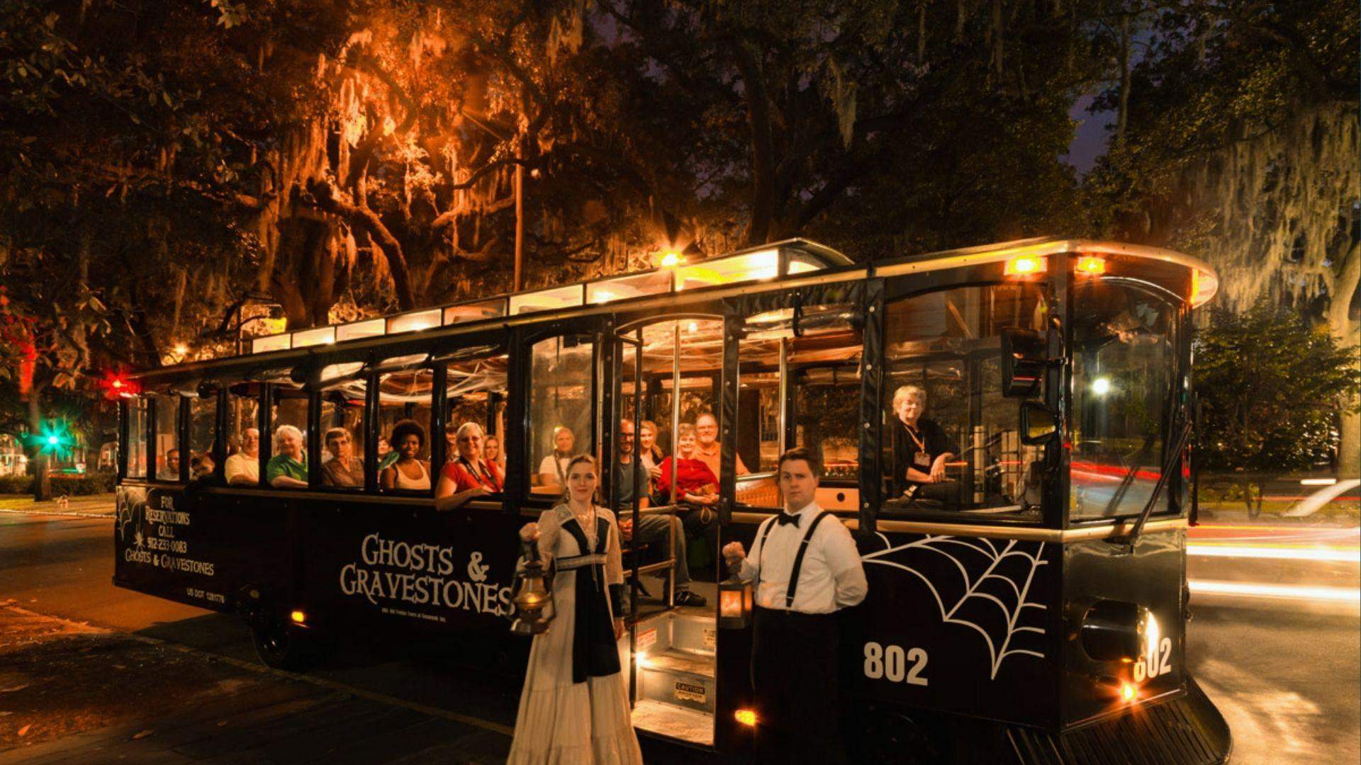 Ghosts and Gravestones trolley tour at night with lantern guides and seated tourists