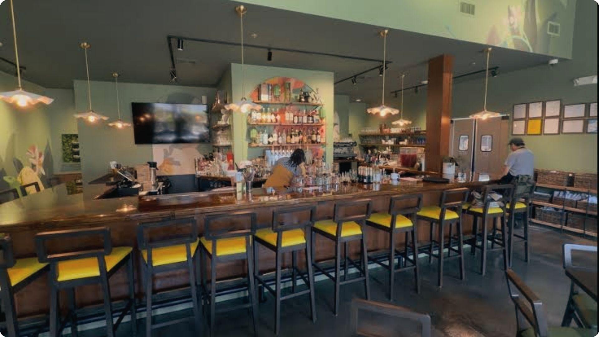 Stylish Savannah bar with yellow stools and stocked shelves ready for evening happy hour cocktails