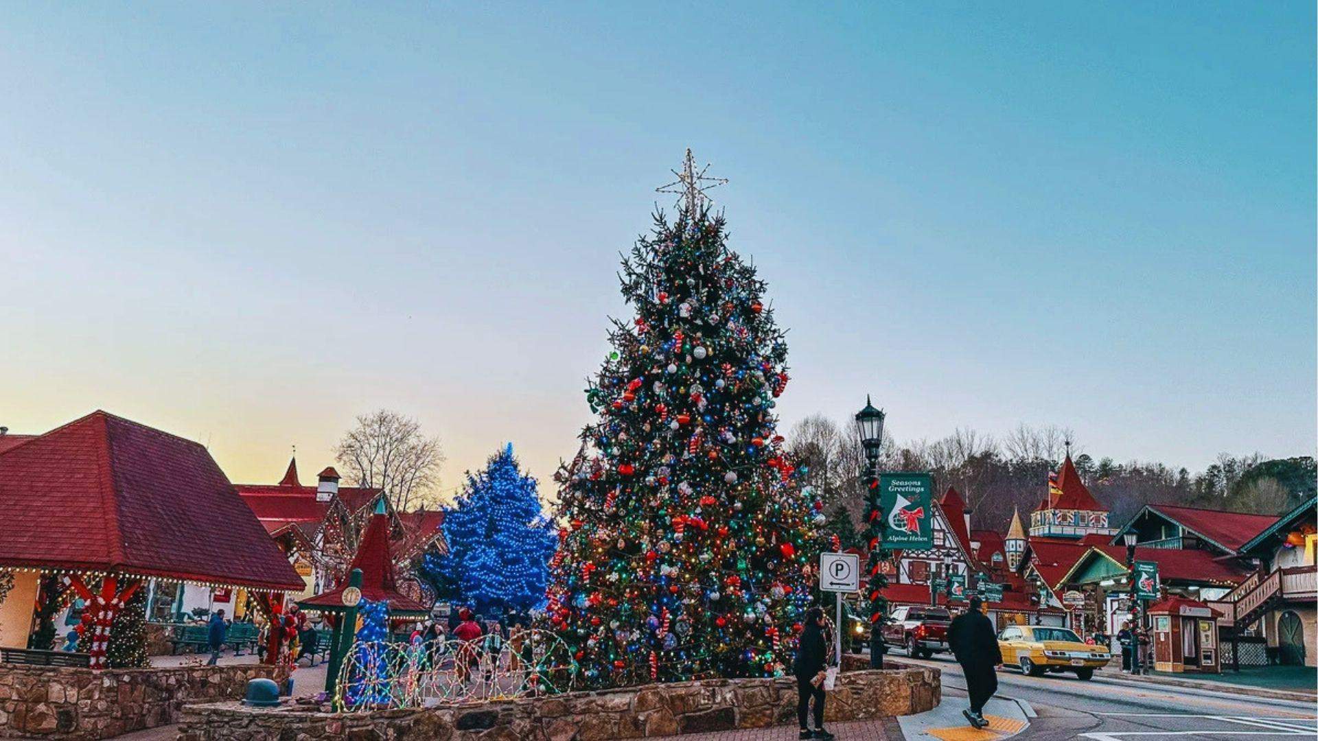 Decorated Christmas tree in traffic island surrounded by Bavarian buildings and holiday lights at sunset.