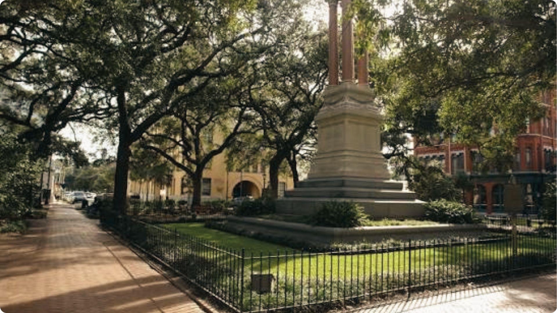 Quiet Savannah square with tall monument under live oaks, peaceful landmark on Savannah walking tour map