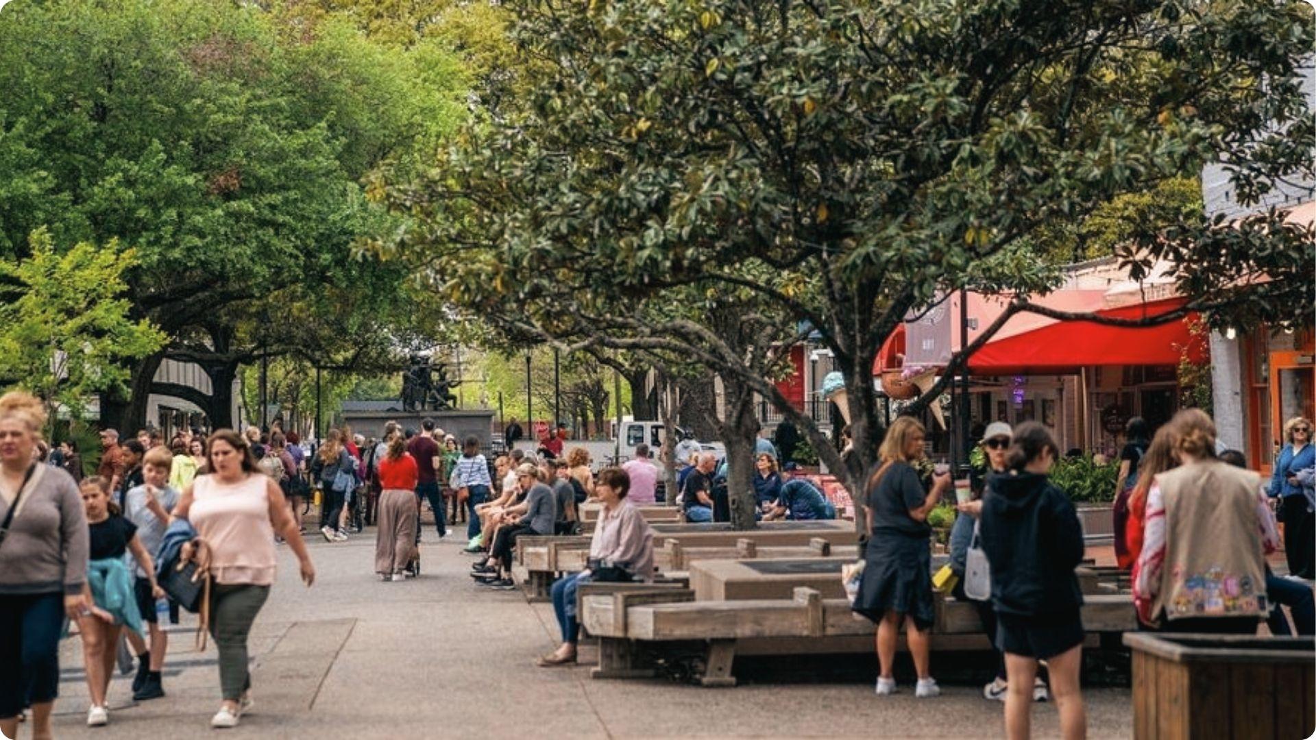 Bustling City Market plaza with oak trees and benches, lively food stop on Savannah walking tour map