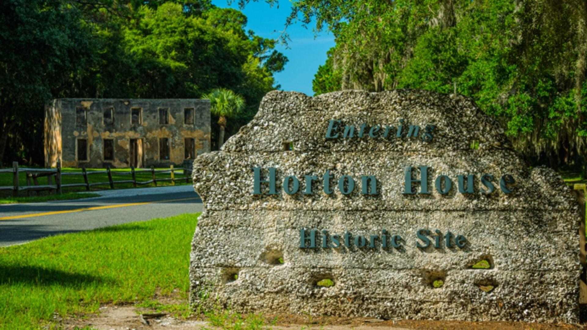 Stone sign reading Entering Horton House Historic Site with tabby ruins and green trees behind