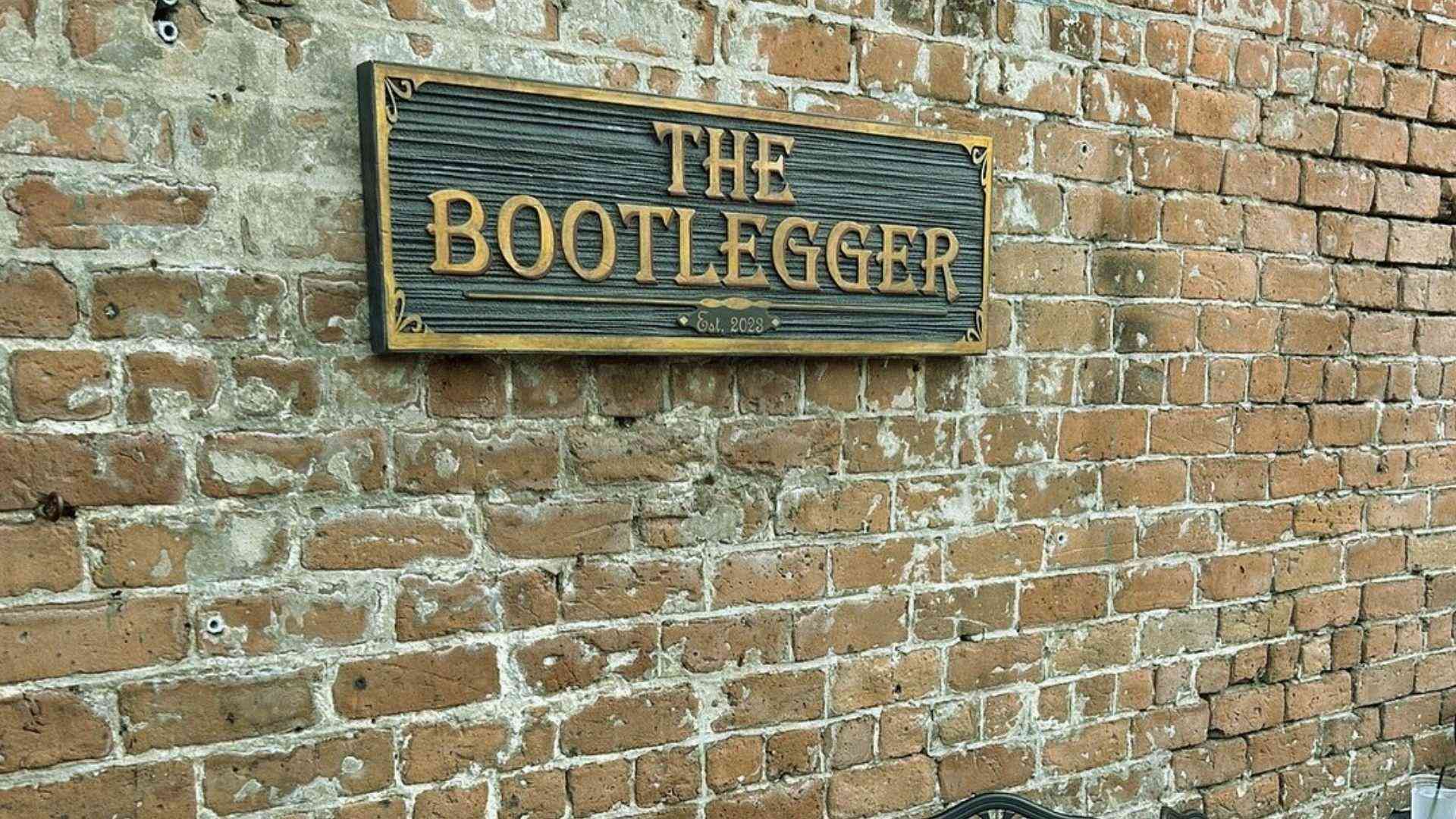 Weathered brick wall with The Bootlegger sign in Savannah.