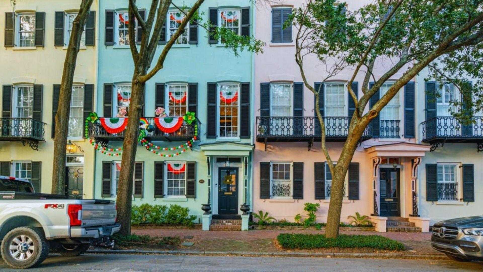 Colorful historic row houses decorated with Irish bunting and garlands along festive Savannah street today.
