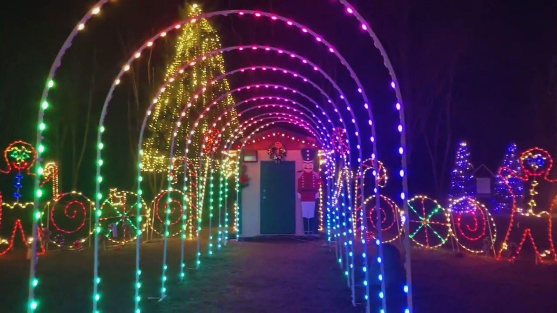 LED light tunnel archway with candy decorations and nutcracker figure at nighttime Christmas festival display.