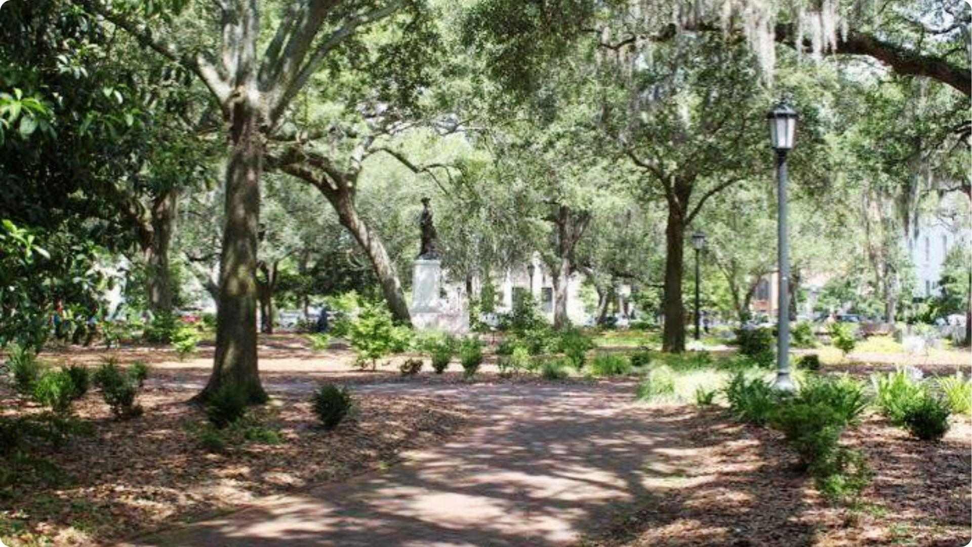 Oak-lined Savannah square path with Spanish moss and distant statue on self-guided walking tour route.