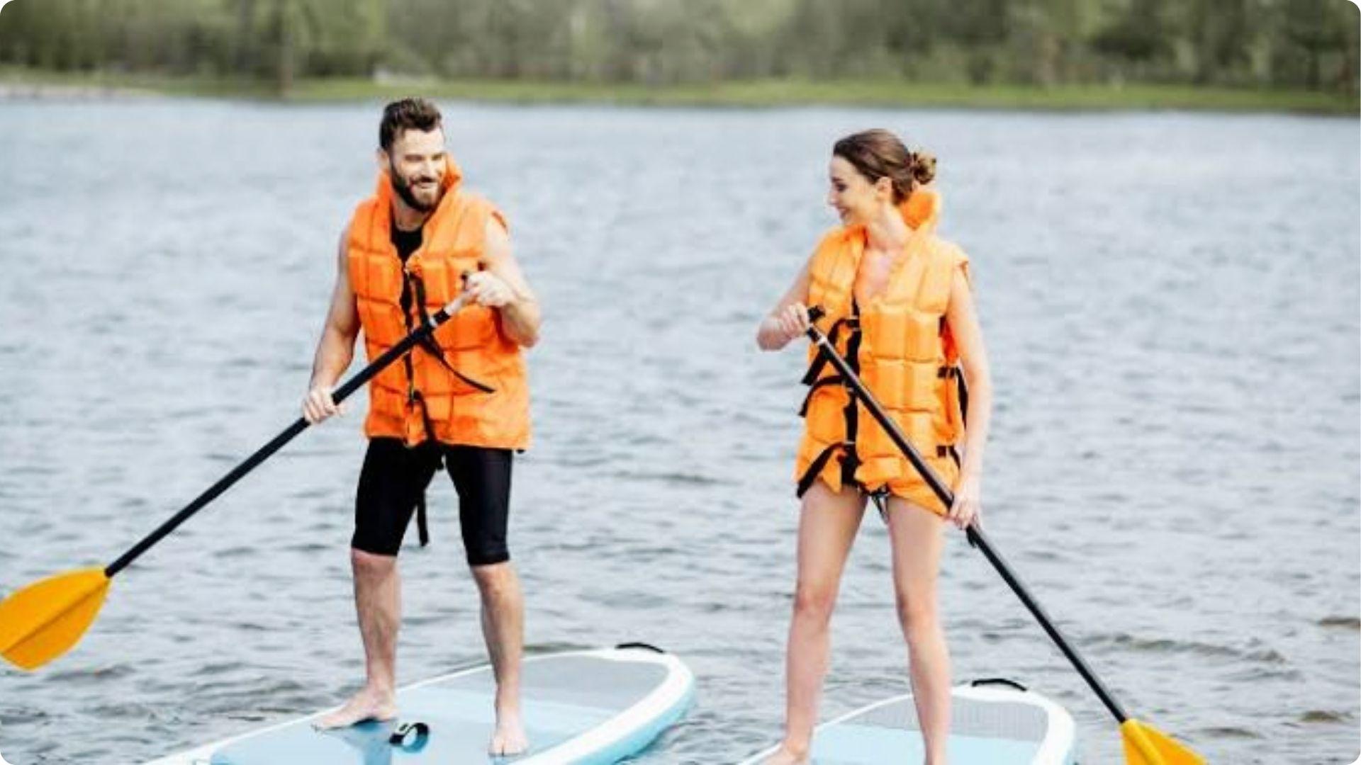 Smiling couple paddleboarding together in orange life vests, fun water adventure in Myrtle Beach