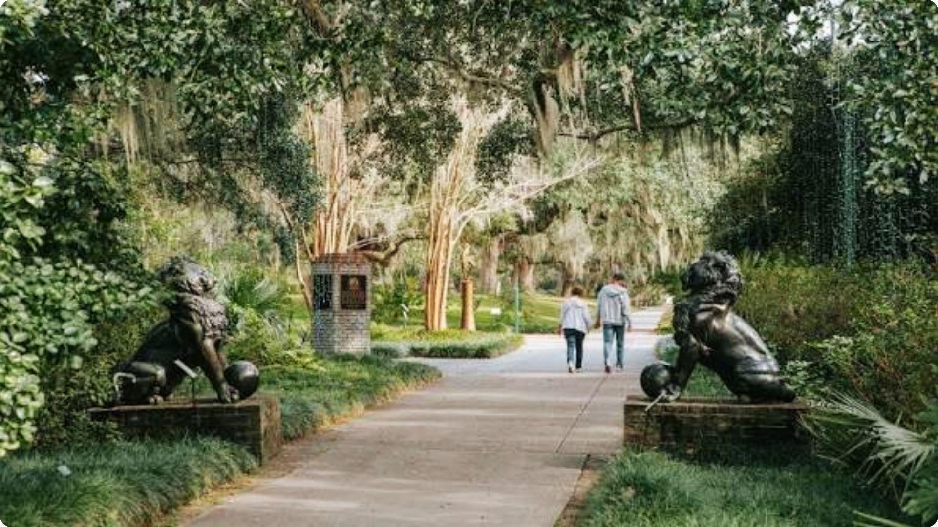 Couple walking hand in hand through sculpture garden with lion statues in Myrtle Beach gardens