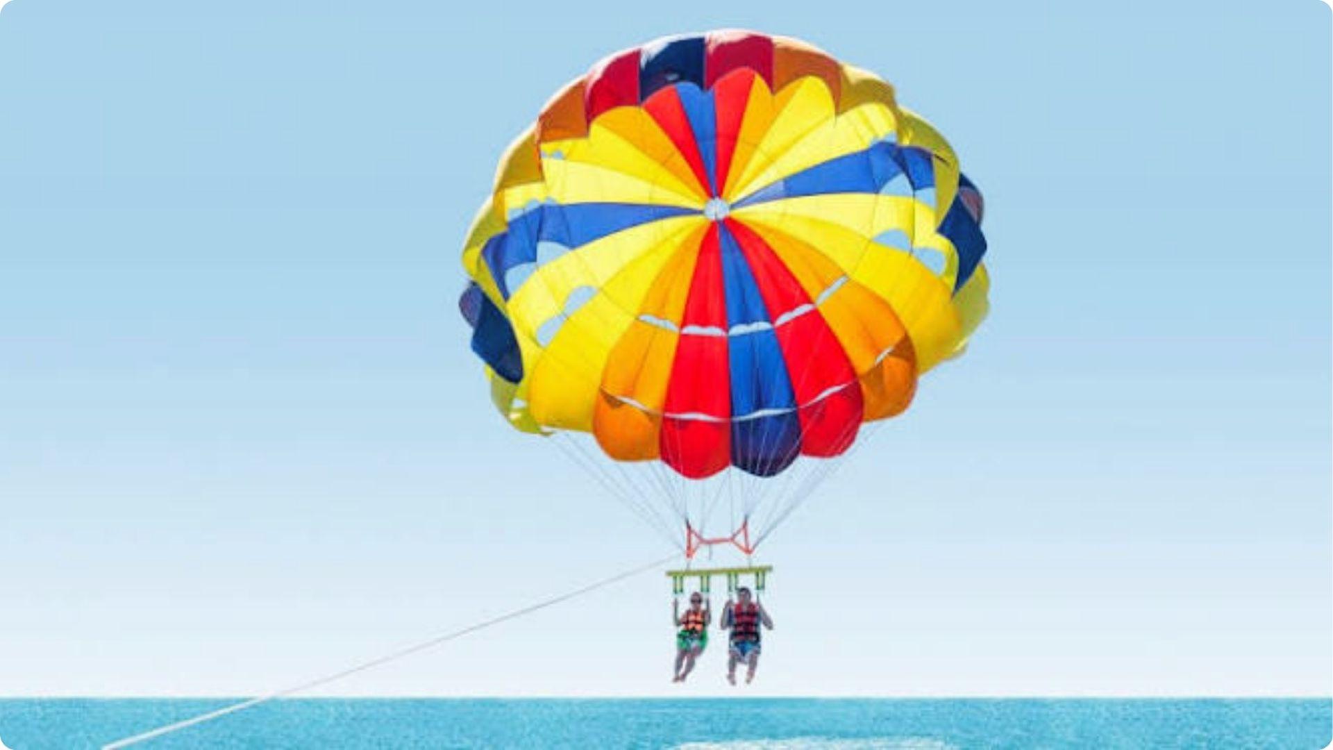 Couple parasailing over turquoise Myrtle Beach waters, vibrant parachute soaring high in blue sky