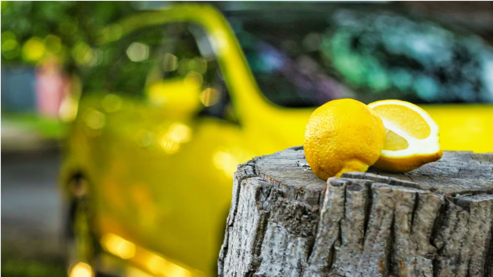 Fresh lemons on tree stump with yellow car indicating lemon law qualification