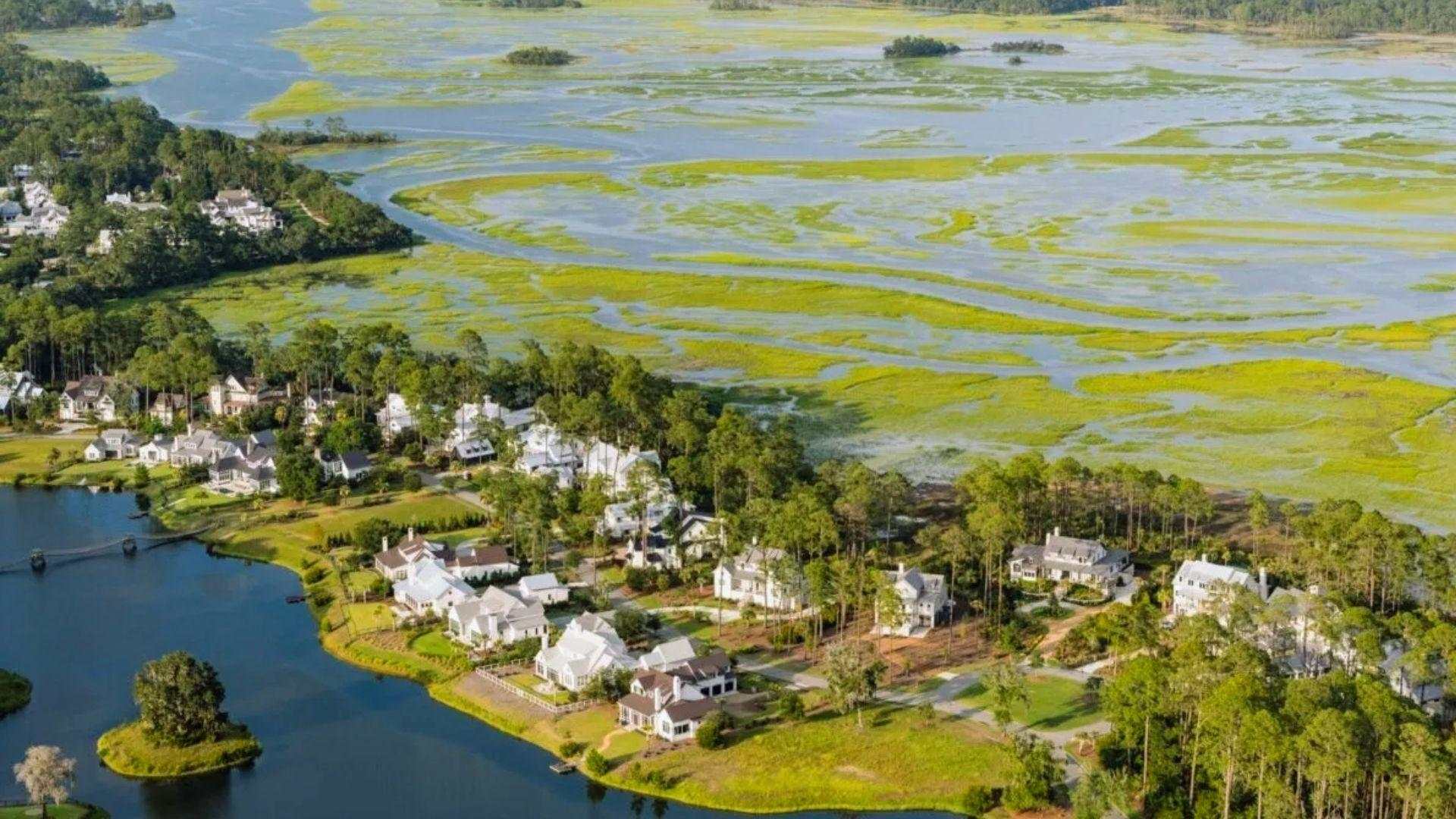 Aerial view of luxury waterfront homes nestled between lake and green tidal marshlands