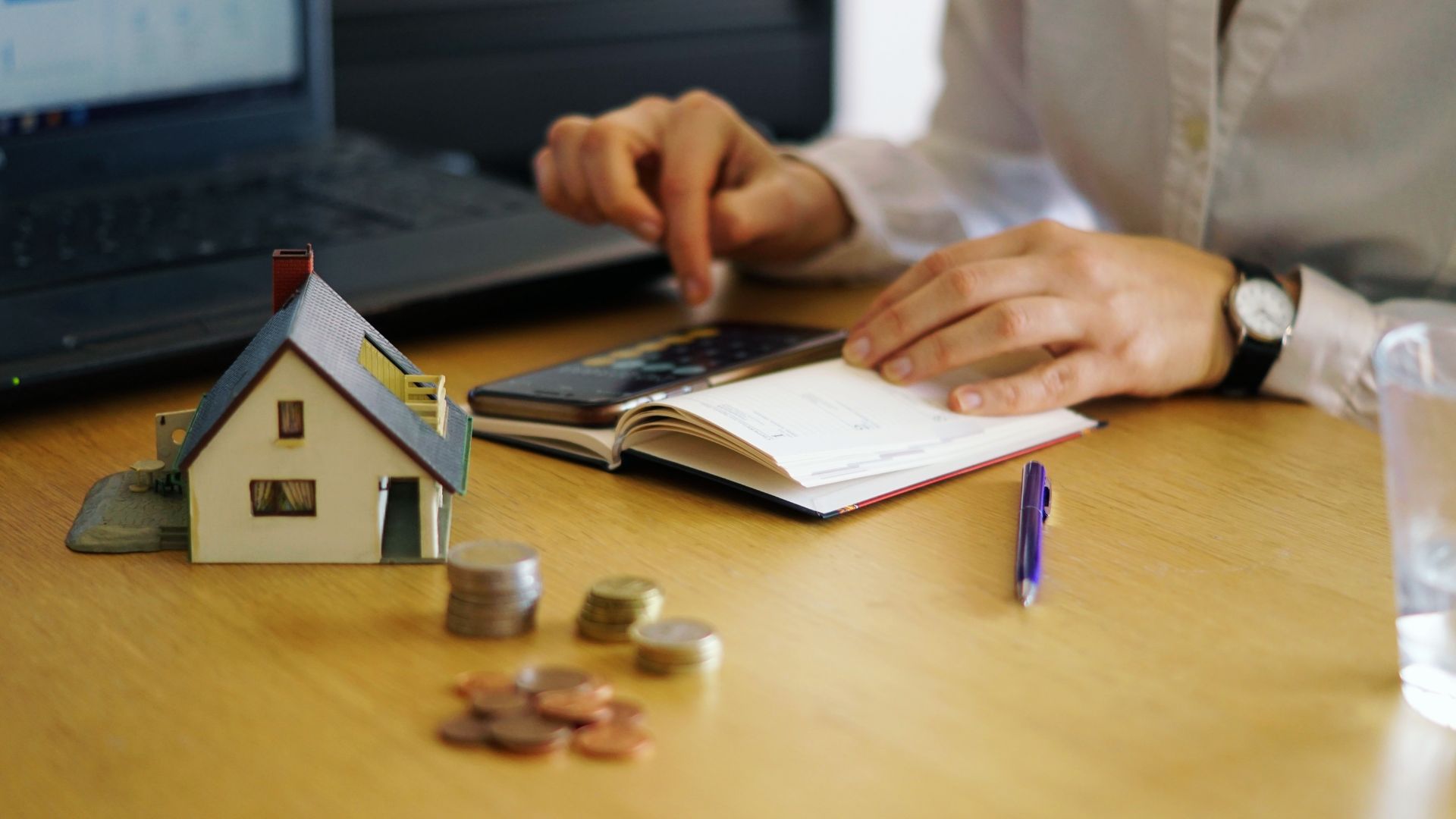 Tenant budgeting with model house and coins showing illegal rent hike in Georgia