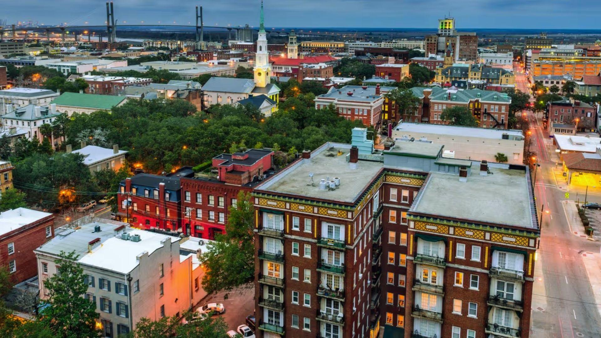 Twilight aerial view of Savannah historic district with illuminated church steeple, Talmadge Bridge