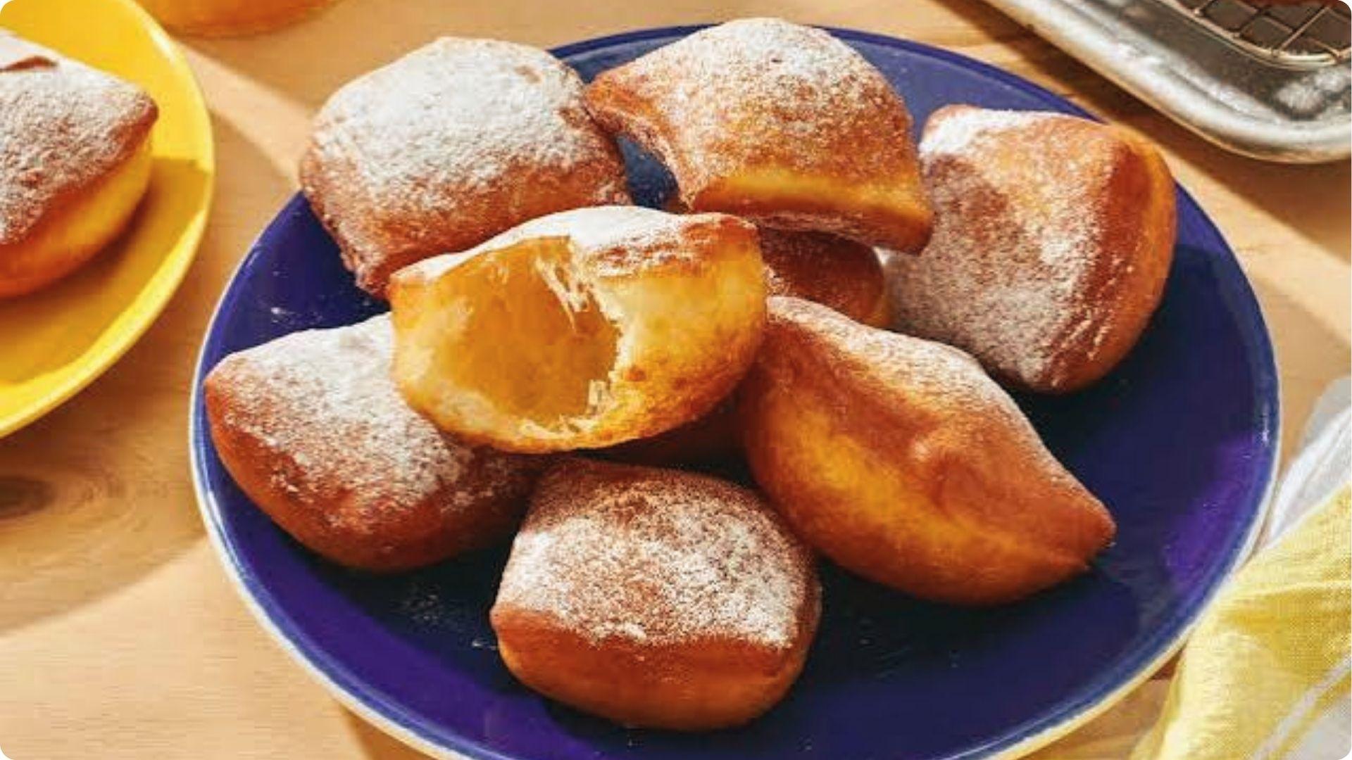 Golden New Orleans beignets dusted with powdered sugar on a blue plate, iconic French Quarter dessert.