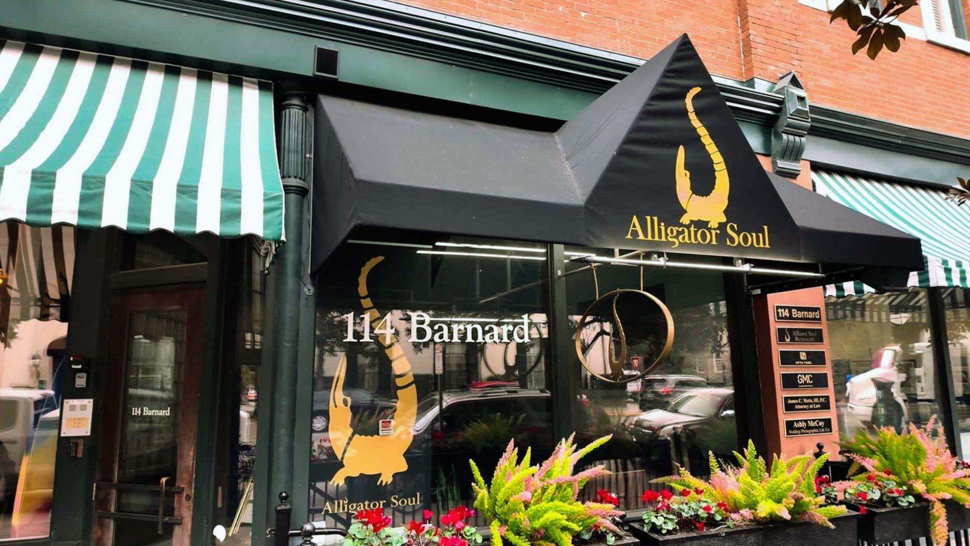 Black awning with gold alligator logo for Alligator Soul at 114 Barnard, flower boxes below.