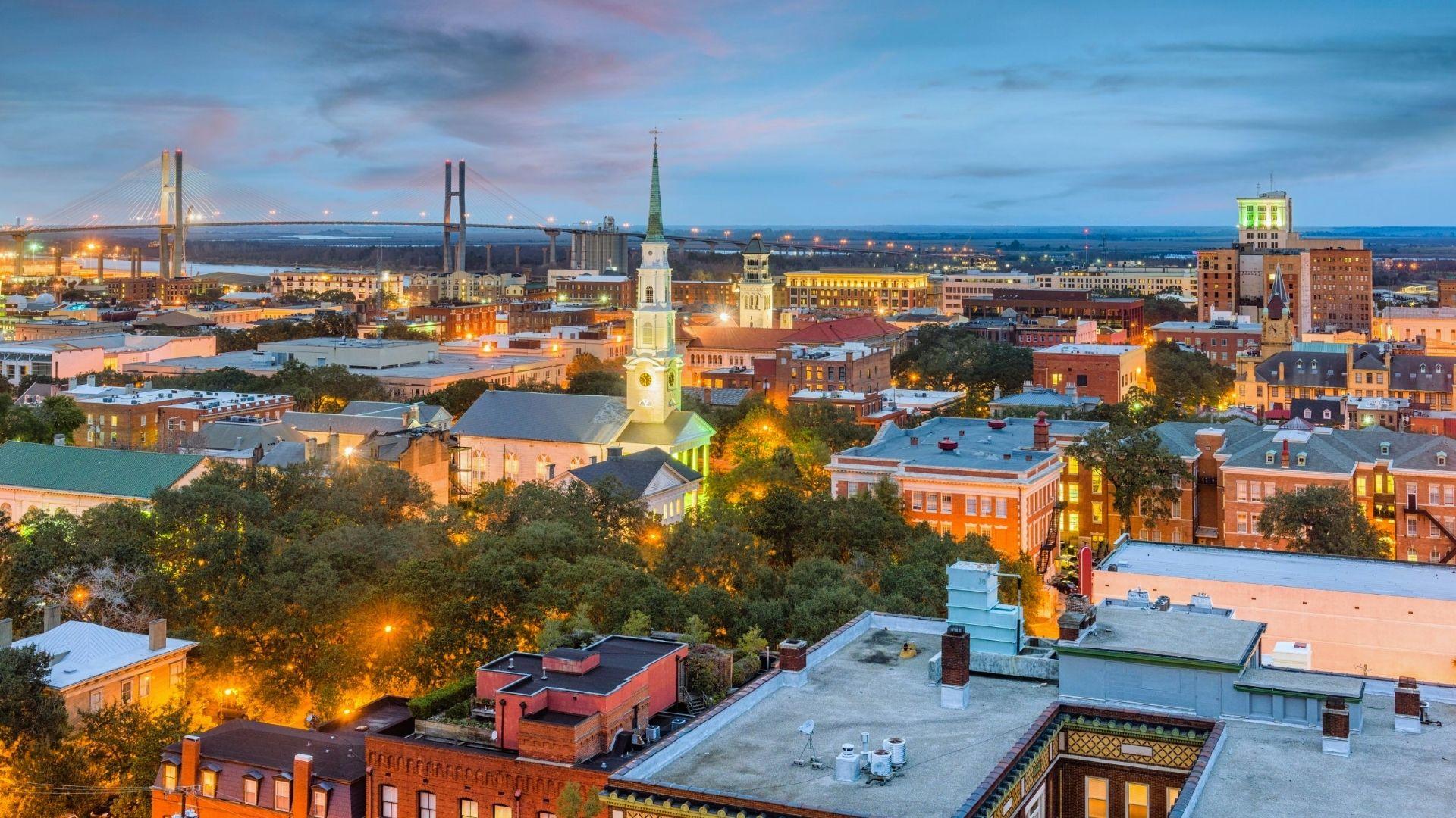 Aerial twilight view of Savannah with illuminated steeple and Talmadge Bridge glowing