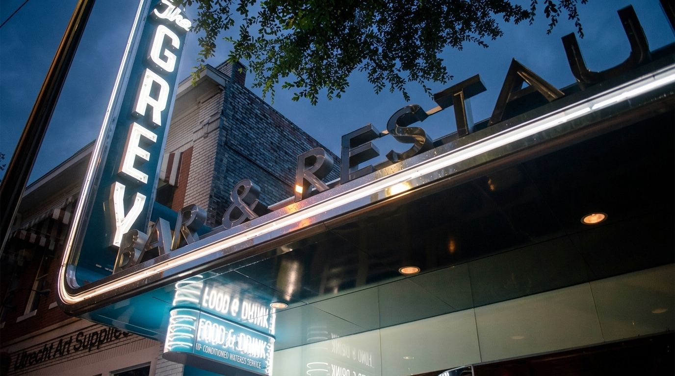 The Grey restaurant sign lit up at night, art deco letters glowing above the entrance.