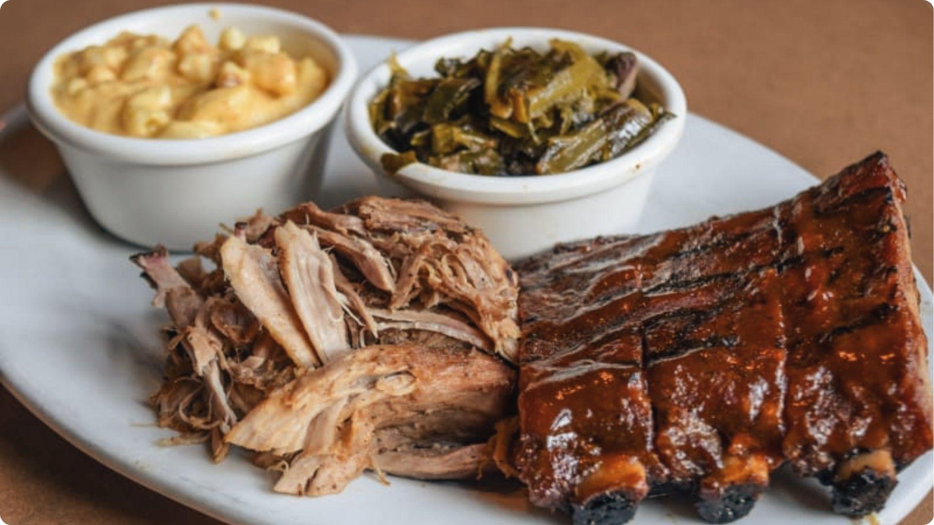 Classic Atlanta BBQ platter with glazed ribs, pulled pork, mac and cheese and collard greens