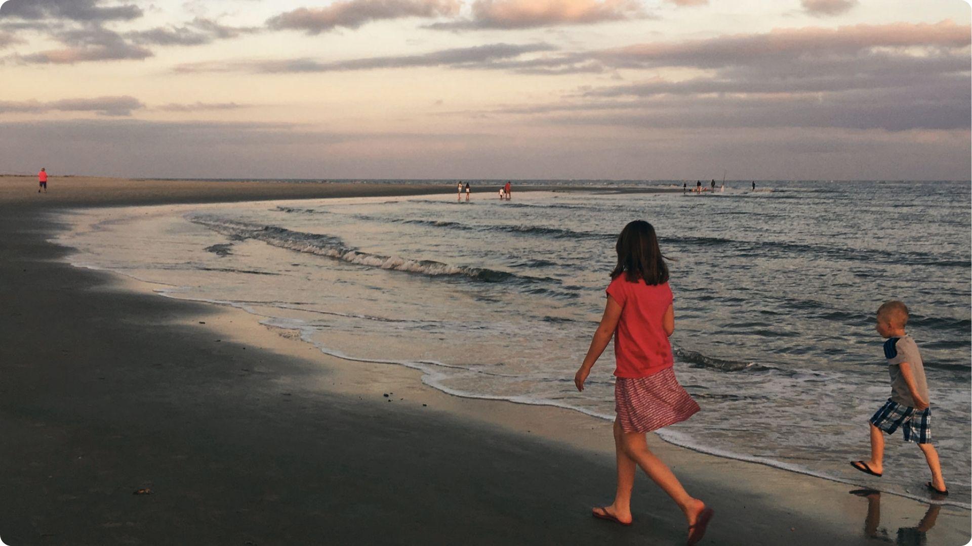 Woman and a toddler strolling near the beach in evening time and enjoying the weather.