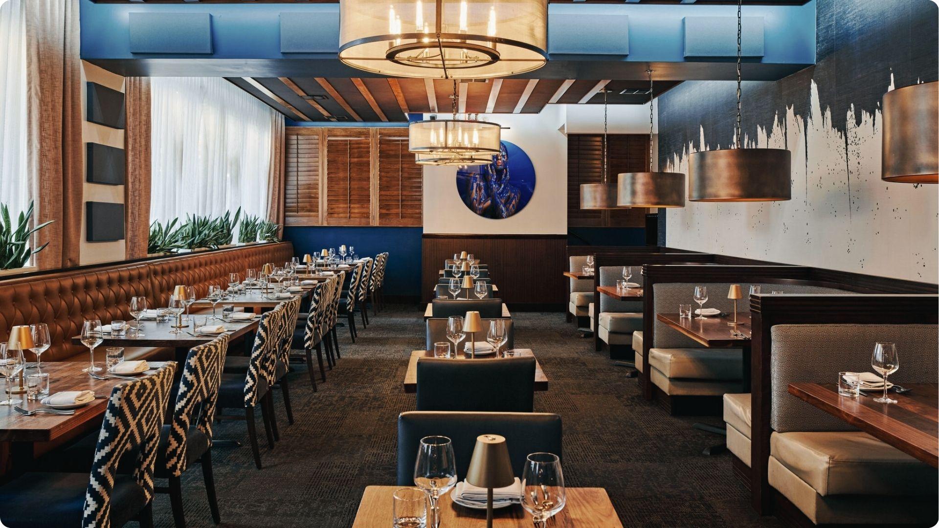 Modern Atlanta steakhouse with leather booths, patterned chairs, warm pendants and wine service