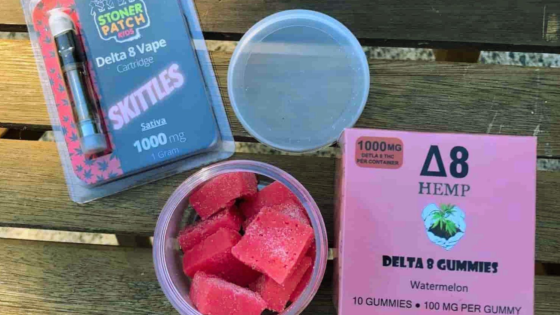 Delta 8 vape cartridge and watermelon gummies in pink box with open container of red gummies