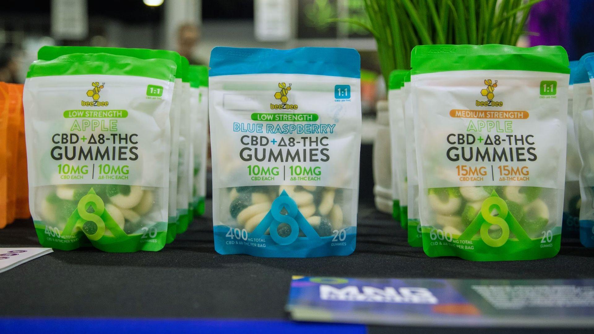 Three standing pouches of beeZbee Apple and Blue Raspberry CBD plus Delta-8 THC gummies displayed on table