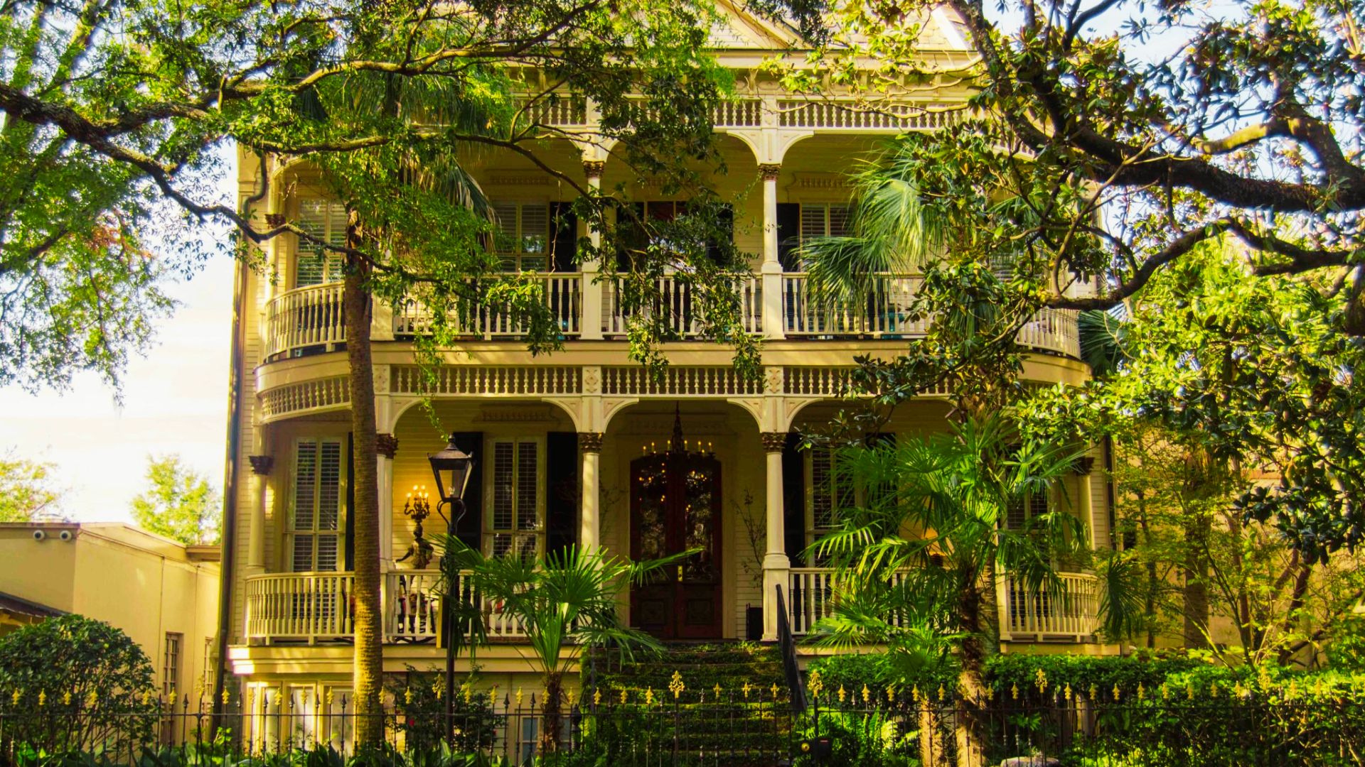 Historic Victorian mansion with wraparound porches among oak trees in Savannah