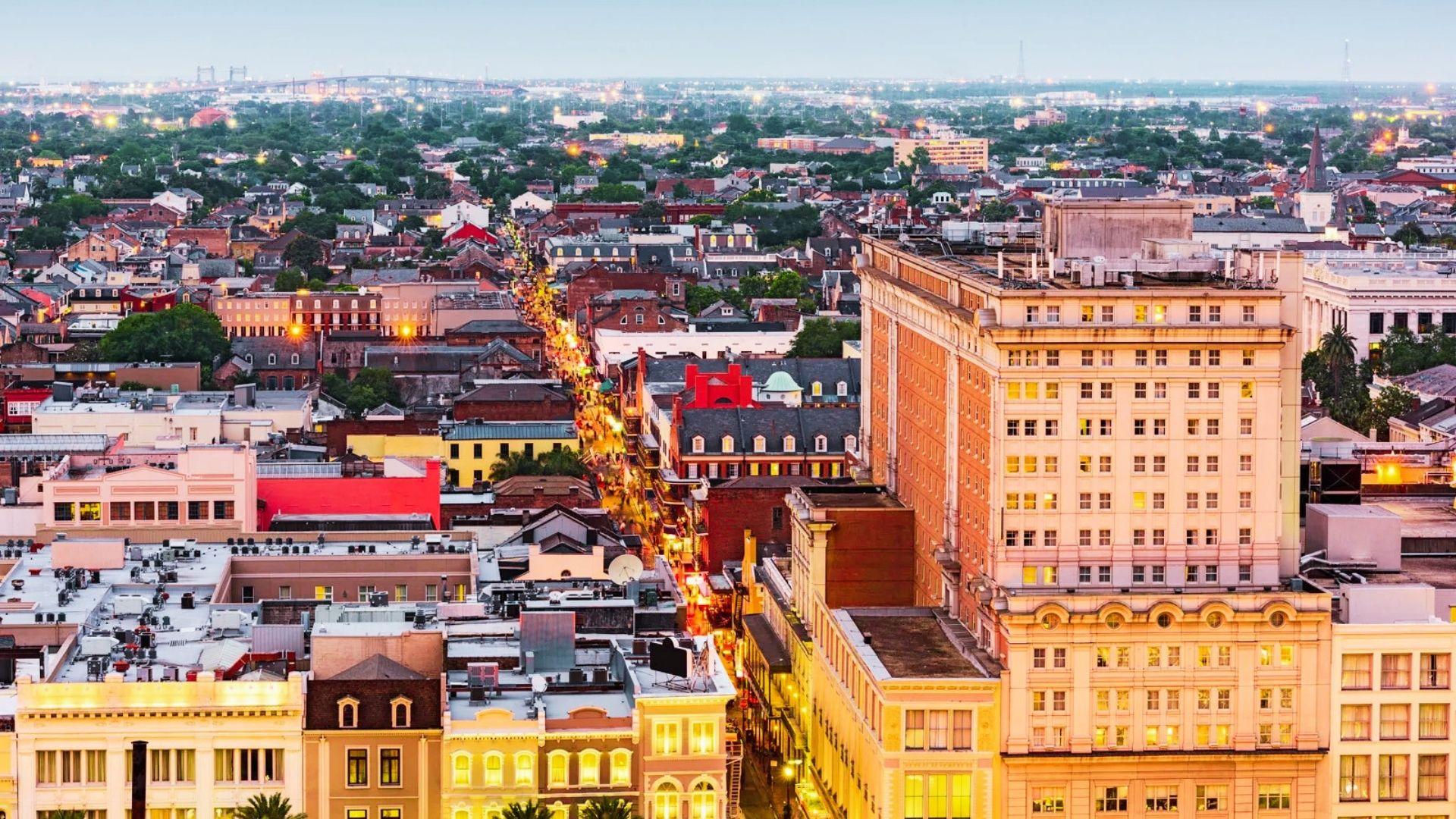 view of New Orleans, highlighting the city's skyline with twinkling lights and a dramatic evening sky.