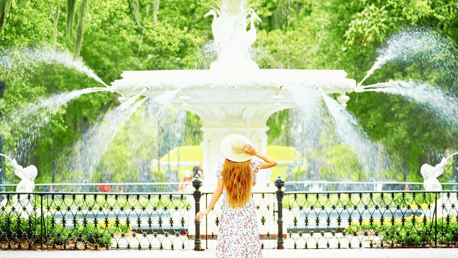 Woman admiring Forsyth Park fountain surrounded by lush greenery in Savannah