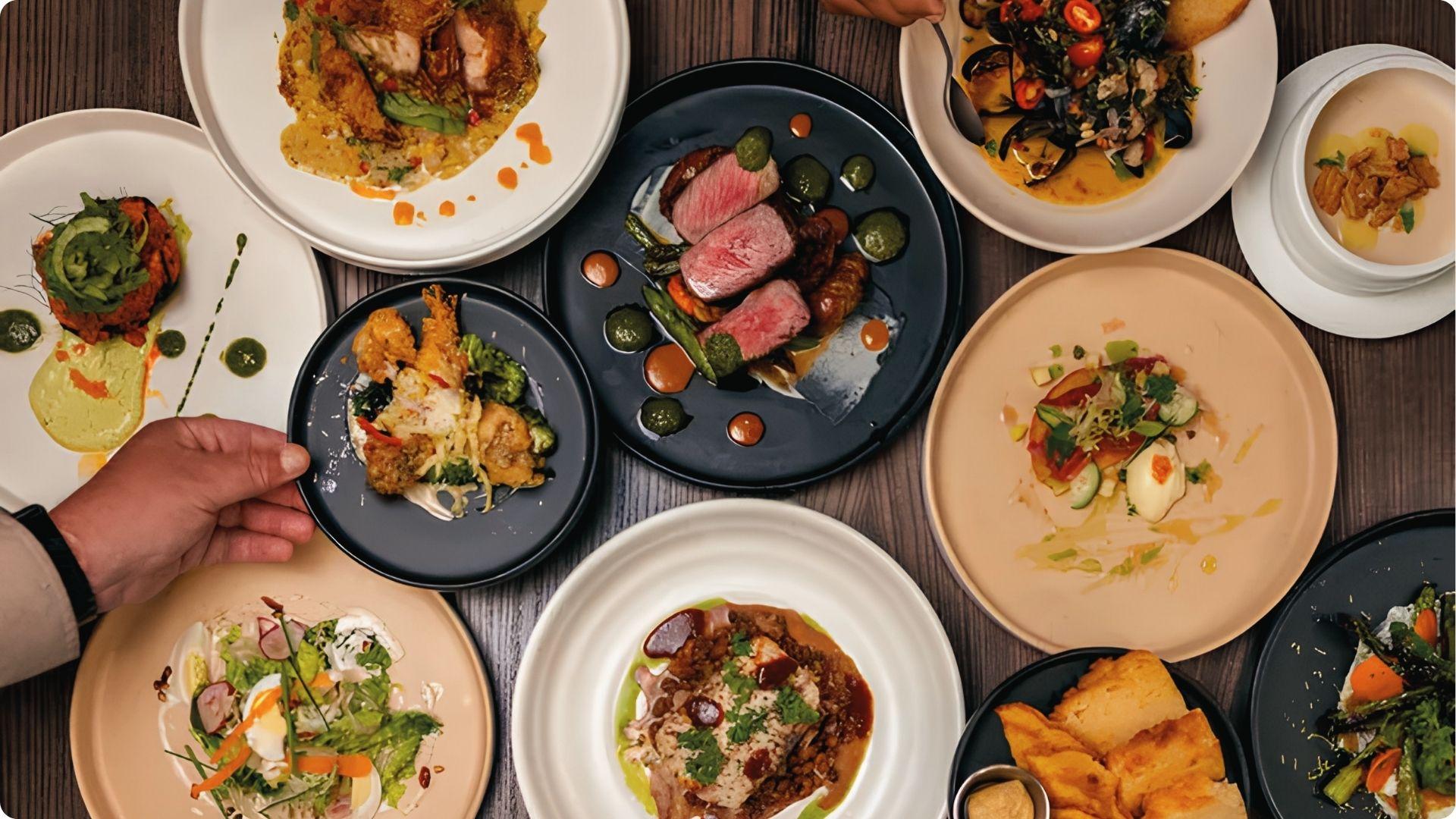 Overhead spread of gourmet dishes at top Atlanta spot with steak, salads, seafood and artful plating